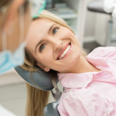 A young women with blonde hair smiling in a dentist chair 