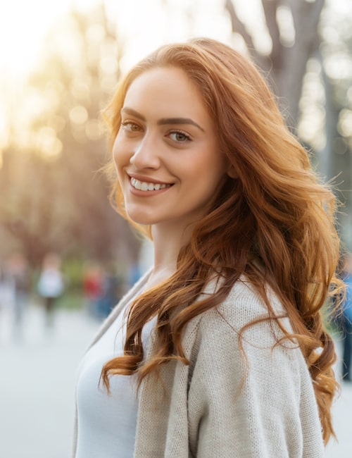 Young girl outside smiling with long auburn hair 