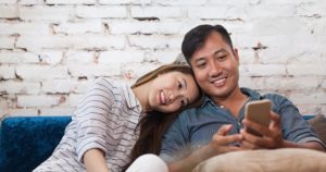 A middle aged couple sitting on a sofa together after enjoying same-day dentistry with CEREC technology
